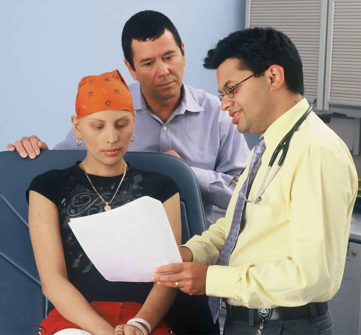 ER clinician reviewing vital signs monitor and explaining fever test results to patient in clinical treatment room with organized medical eq